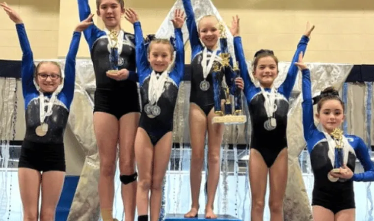 A group of gymnasts posing on the podium