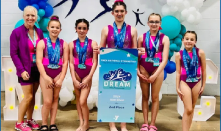 A group of Strivers gymnasts posing with a 2nd place banner
