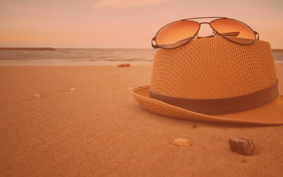 Sandy beach with a sun hat in the foreground.